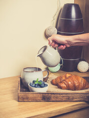 romantic breakfast with fresh croissants coffee,milk and berries on wooden table