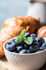 romantic breakfast with fresh croissants coffee,milk and berries on wooden table