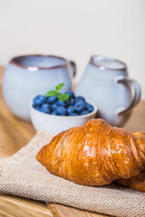 romantic breakfast with fresh croissants coffee,milk and berries on wooden table