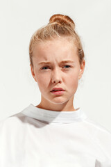Fototapeta premium Young blonde girl emotionally poses in white T-shirt on white background