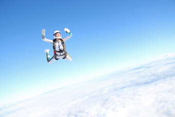 Skydiving. A happy girl is flying in the blue sky.