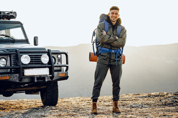 Naklejka premium Portrait of a young traveler man in hiking equipment standing near his off-road car