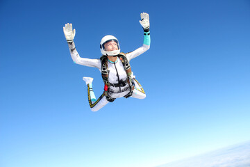 Skydiving. A happy girl is flying in the blue sky.