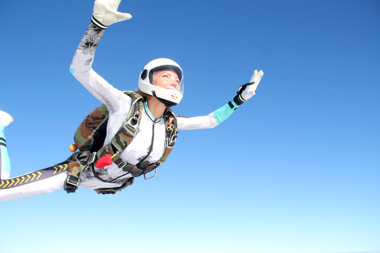 Skydiving. A happy girl is flying in the blue sky.