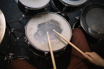 Close-up view of professional drum set and hands. Hands of male drummer holding drumsticks sitting...