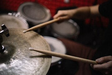Male hands with drumsticks playing drum set. Cropped male drummer holding wooden drumsticks and playing drums kit.