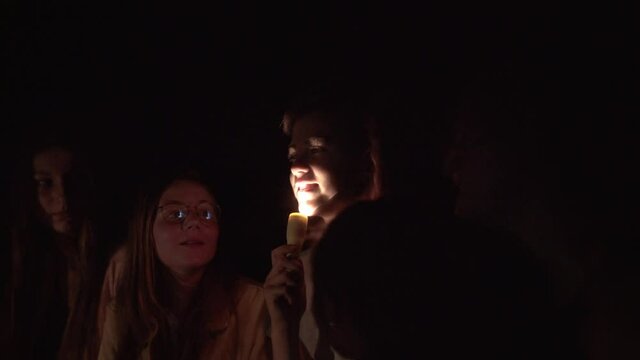 Teenager telling scary story using flashlight on face.