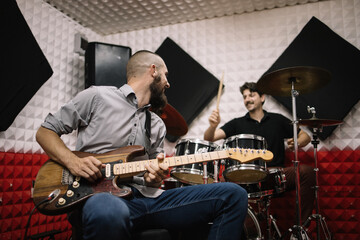 Guitar player and drummer playing music instruments. Rock band members playing guitar and drum set...