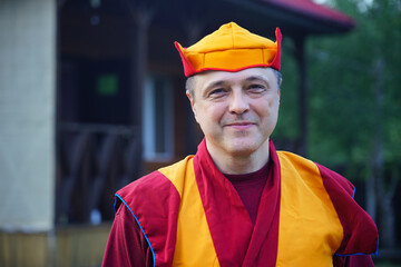 portrait of a monk in red clothes and a hat