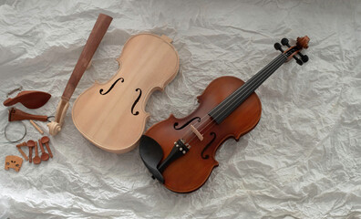 Raw violin put beside completed violin,on background