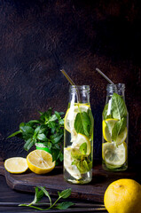 Fresh mojito drinks in bottles and ingredients - lemon and mint