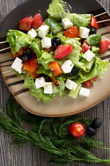 Greek salad on a striped plate on the table in the cafe