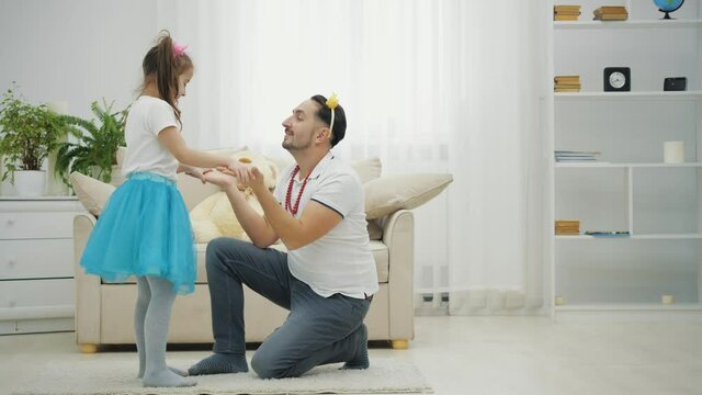 Father is dancing with his daughter. Little ballerine is dancing around.