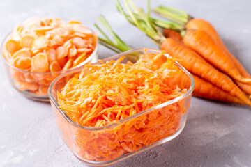 Frozen grated carrots in a glass container on a light background
