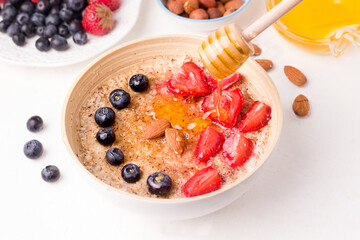 Summer breakfast of porridge with berries, nuts and honey.