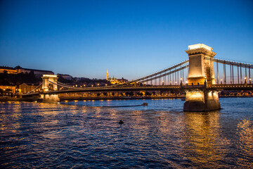 Fototapeta premium The Szechenyi Chain Bridge crossing the Danube river and St. Matthias Church at dusk, Budapest, Hungary