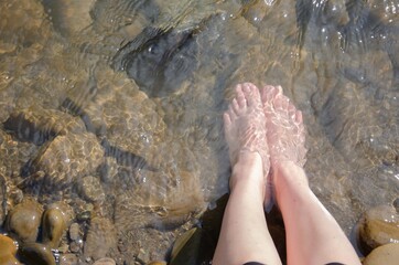 Female feet in the water. Water spa treatments. Foot stones river.
