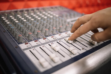 Close-up view of cropped man adjusting mixing controller. Human hand setting channels on audio...