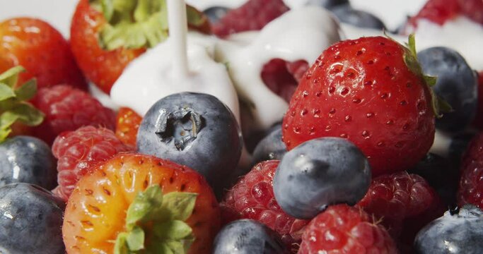 Pouring Strawberries, Raspberries and Blueberries With Yogurt in Slow Motion. Fresh berries are poured with yogut.