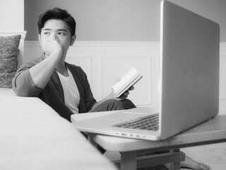 Young asian man reading a book while relaxing at home in black and white