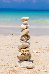 Fototapeta na wymiar Pyramid of stones on a sandy beach. White sand, coral beach. The concept of life balance, harmony and meditation. stability, zen, harmony, balance.