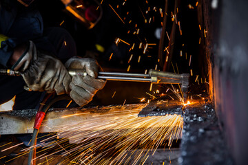 Worker cutting metal steels by Gas Cutting Torch. He cutting the iron plate in the confined spaced.