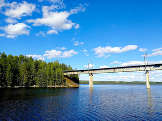 A bridge across the lake strait in Central Finland. Beautiful colorful summer landscape with blue sky and fluffy clouds.