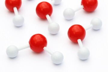Plastic ball-and-stick models of water molecules on a white background. Water molecules consist of...