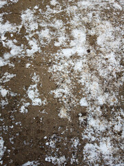 The ground, stones and snow of the road in the spring time, look like a background image in close-up.