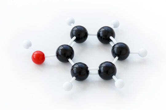 Plastic ball-and-stick model of a phenol molecule (C6H5OH), shown with kekule structure on a white background.