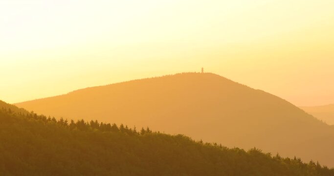 Zoomed inside sunset over the mountainous landscape of the sun in the background of orange color moving trees on the hilltop area of Beskydy Pustevny.