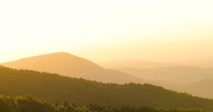 Zoomed inside sunset over the mountainous landscape of the sun in the background of orange color moving trees on the hilltop area of Beskydy Pustevny.