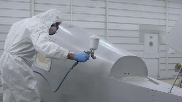 Man paint spraying on an aircraft fuselage, slowmotion, 3