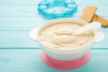 Bowl with baby food with toys on blue background