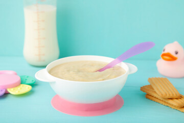Bowl with baby food with toys on blue background