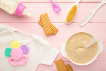 Bowl with baby food with toys on pink background