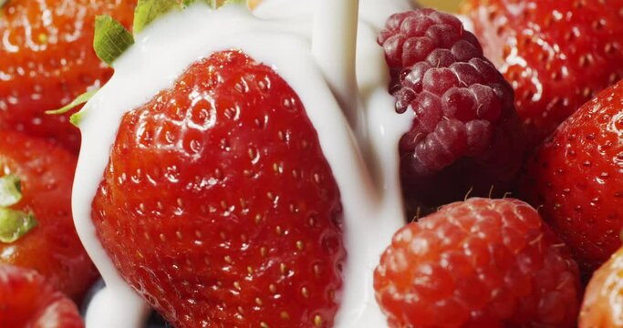 Pouring yogurt on fresh berries in slow motion. Pouring Strawberries, Raspberries and Blueberries With Yogurt in Slow Motion. Fresh berries are poured with yogut.