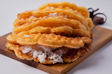 Coconut waffle on a wooden cutting board, white background