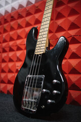 Fototapeta premium Black electric guitar propped on wall in soundproof studio. Close-up portrait of shiny guitar on wall in music recording studio.
