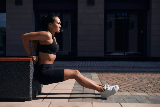 Young sporty teenage model pumps and crunches the abdominals and posing on playground near horizontal and parallel bars.