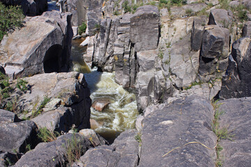 Natural texture. Geology. The rapids. Gray stone precipice. View of the river flowing along the rocky cliffs in the mountain forest. 