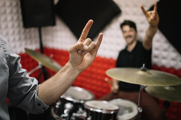 Fototapeta na wymiar Male hands showing rock and roll hand sign. Men in soundproof studio showing sign of the horns.