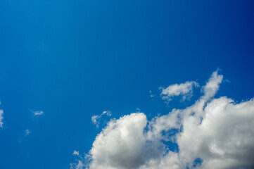Fototapeta na wymiar White beautiful Clouds in the lower right corner against a dazzling blue sky