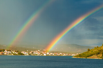 Fototapeta na wymiar Rainbow over the sea bay near The Rogoznica village, a popular tourist destination on the Dalmatian coast of Adriatic sea in Croatia, Europe.