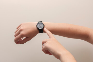 The girl has a watch on her hand. She shows the time with her finger.