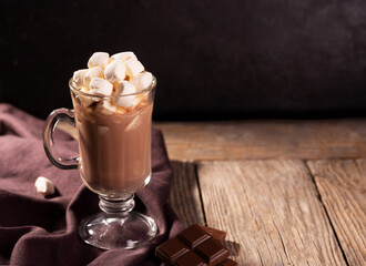 Hot chocolate with cinnamon and marshmallow on wooden background
