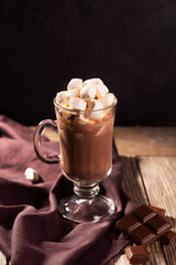 Hot chocolate with cinnamon and marshmallow on wooden background