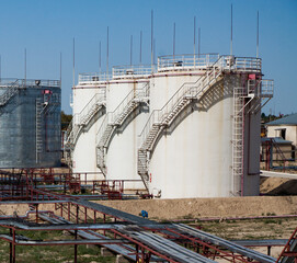 White oil storage tanks on oil refinery plant in desert. On bright sun and blue sky background. Near Taraz city, Kazakhstan.