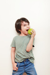 niño pequeño hispano  dándoleun mordisco a manzana verde