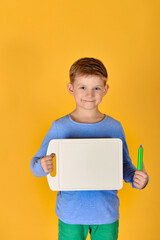 A boy is standing with a blank white board and a pencil.